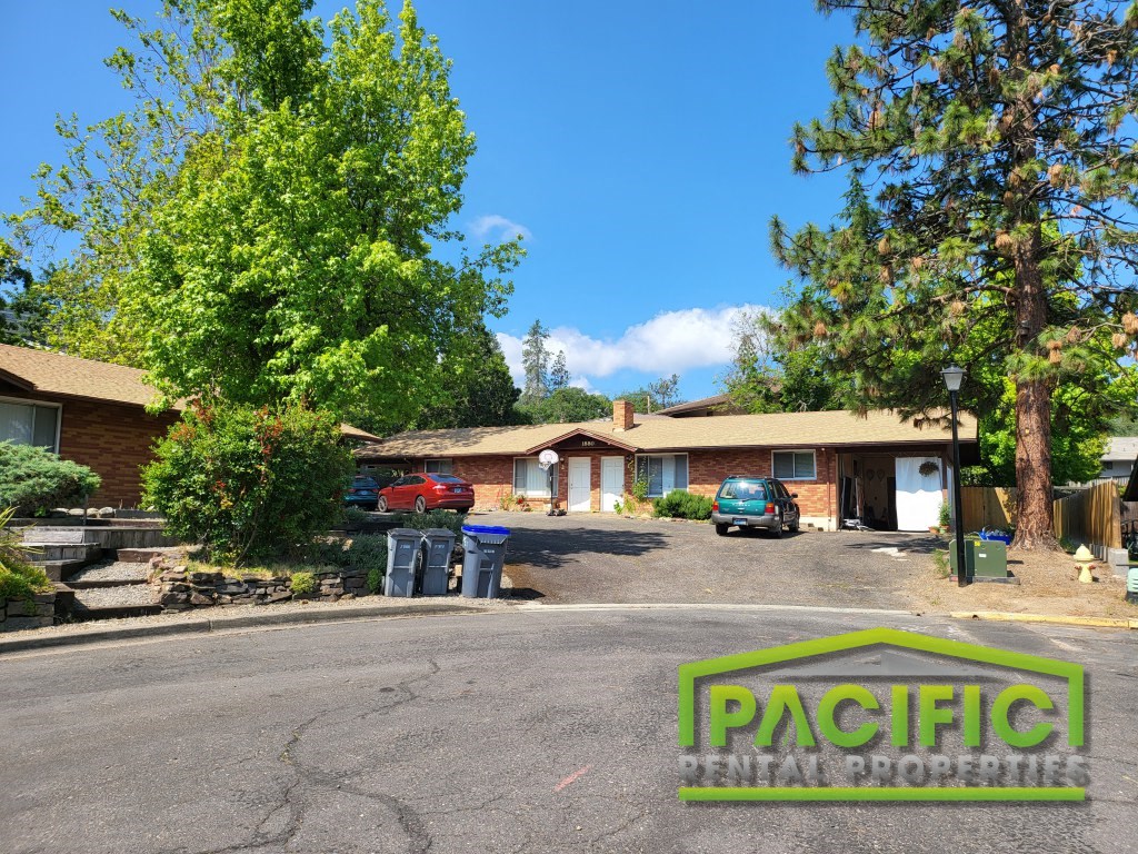 a parking lot in front of a house with cars parked