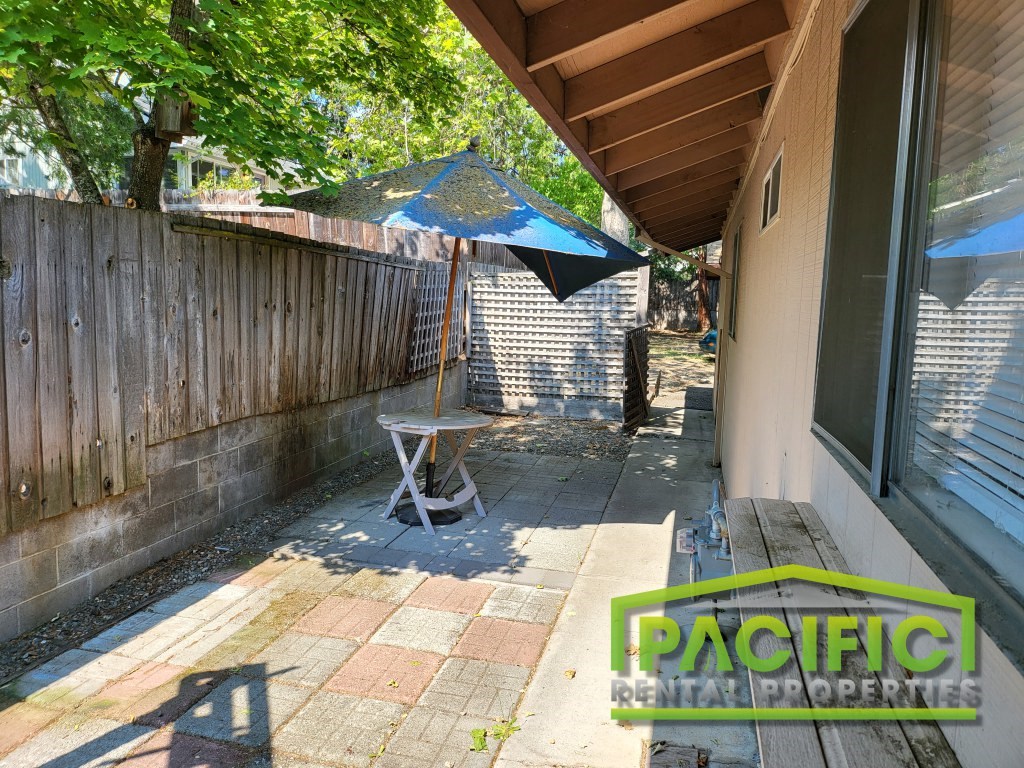 a backyard patio with a table and an umbrella