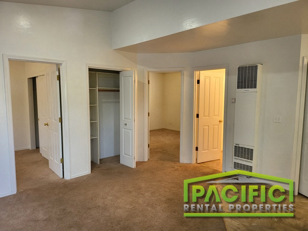 an empty living room with many doors and a carpeted floor