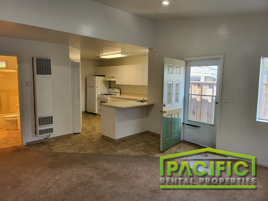 an empty kitchen with an open door into the living room