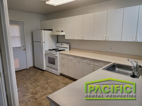 a kitchen with white cabinets and a sink and a refrigerator