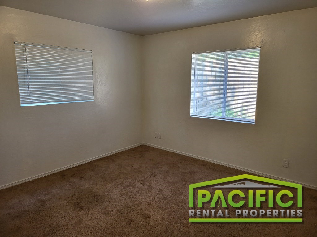 an empty room with a carpet and two windows