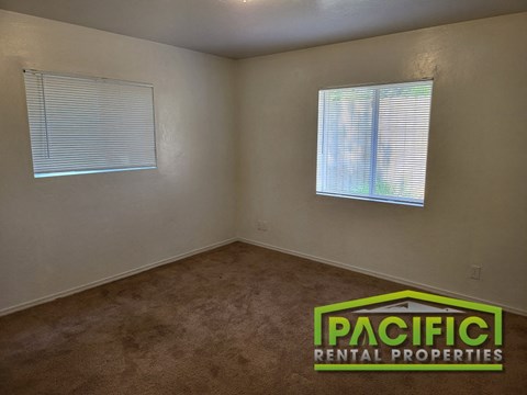 an empty room with a carpet and two windows