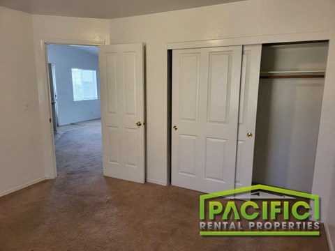 a bedroom with two closets and a carpeted floor and a door to a