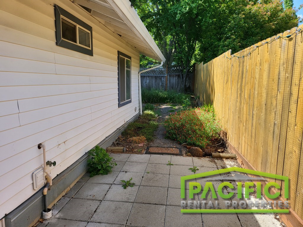 the side of a house with a backyard with a patio and a fence