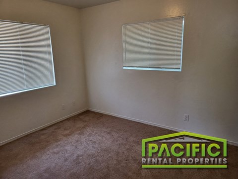 an empty room with two windows and a carpeted floor