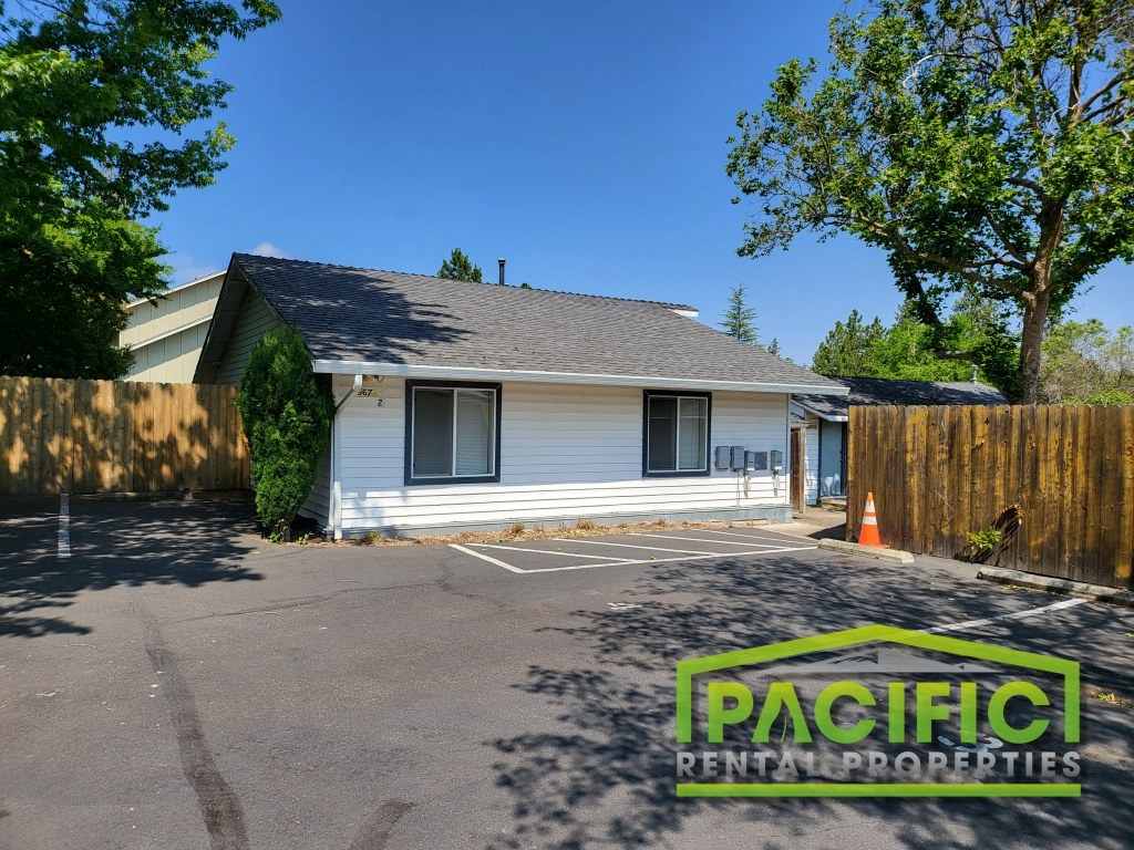 a small white house in a parking lot with a fence