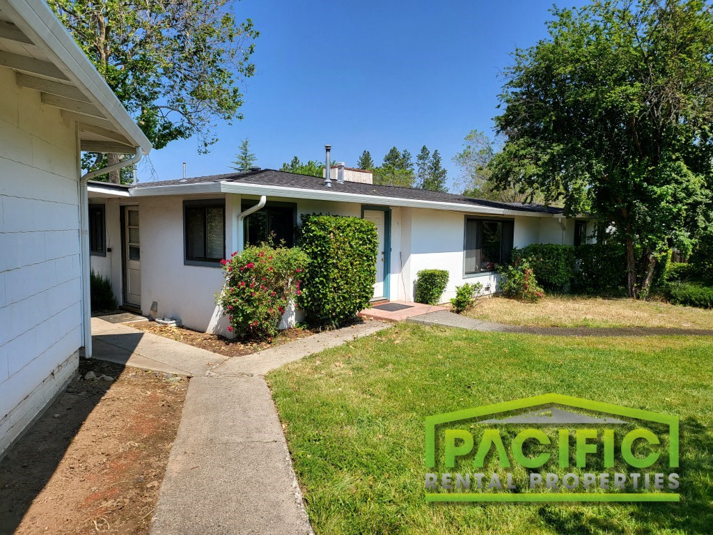 a small white house with a yard and a sidewalk