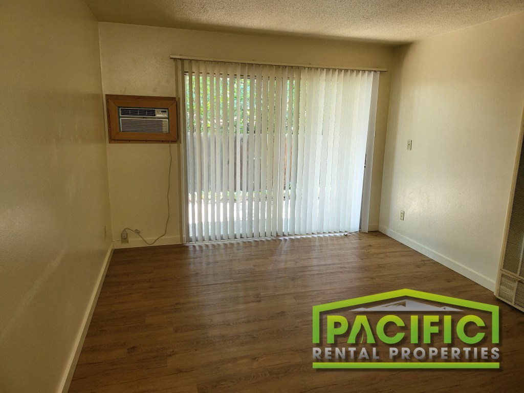 an empty living room with a sliding glass door and wooden floors