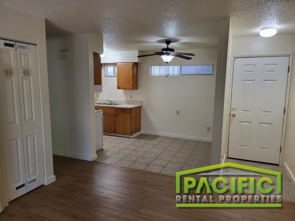 an empty living room and kitchen with a ceiling fan