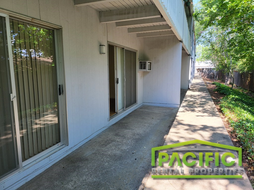a side view of a building with a porch and a sidewalk