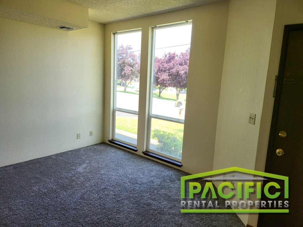 a living room with a large window and carpeted flooring