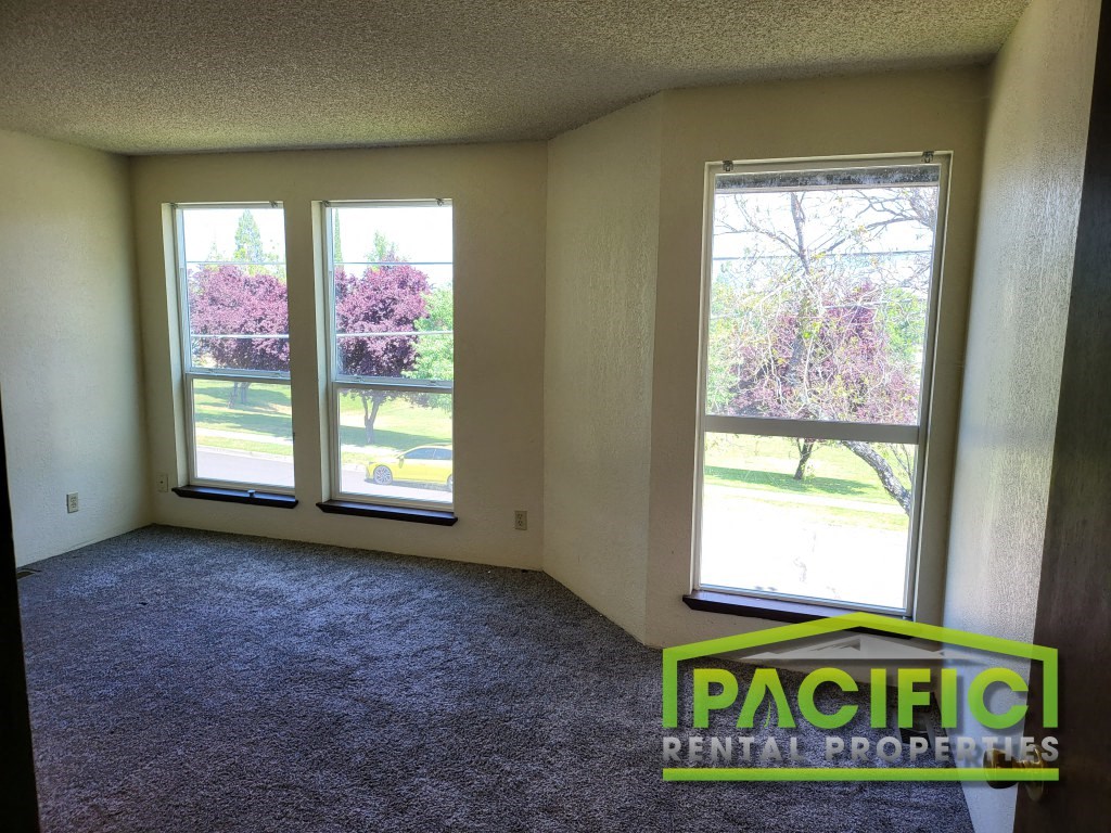 an empty room in a house with three windows