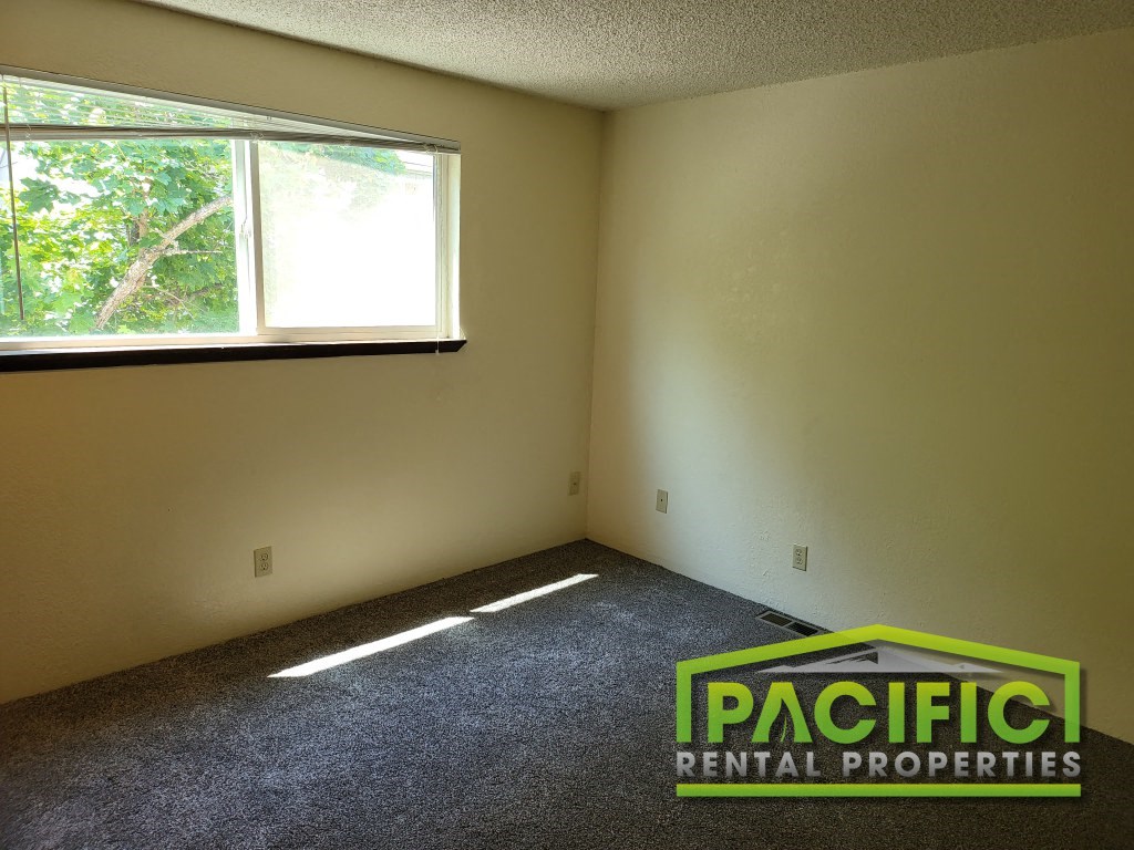 an empty room with a window and carpet in it