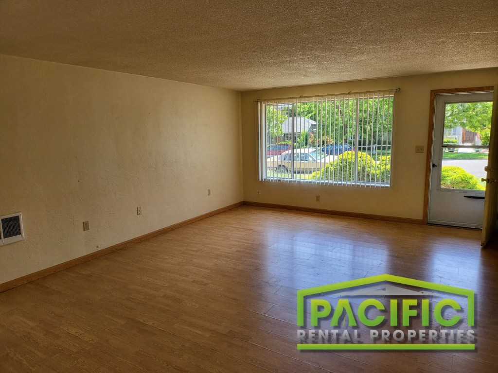 an empty living room with wood floors and a large window