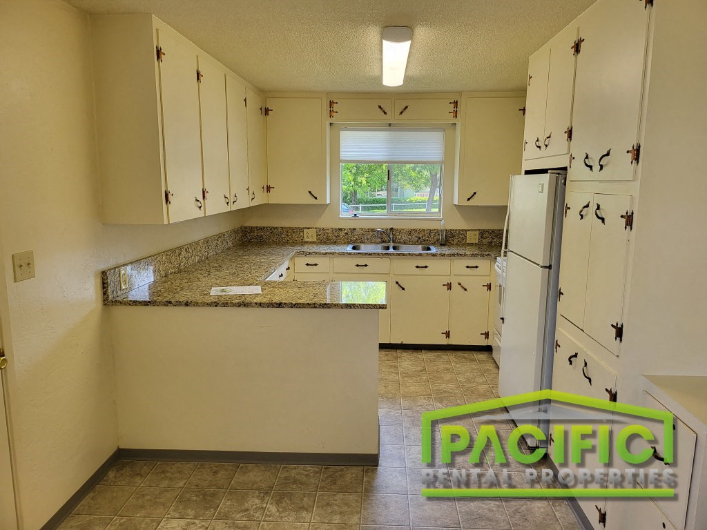 a kitchen with white cabinets and a white refrigerator