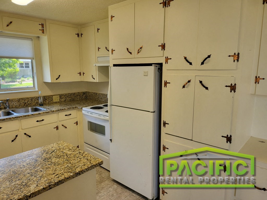 a kitchen with white cabinets and a white refrigerator