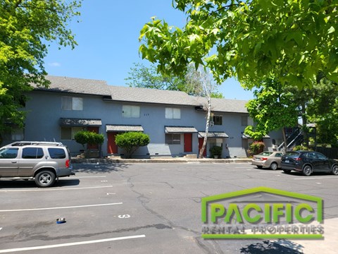 a parking lot in front of a blue building with cars parked
