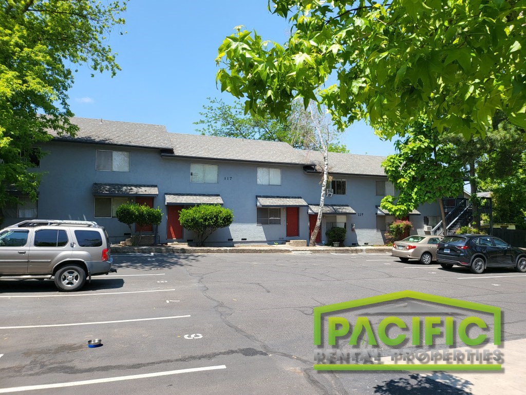 a parking lot in front of a blue building with cars parked