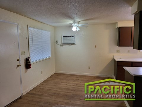 an empty kitchen with a ceiling fan and a window
