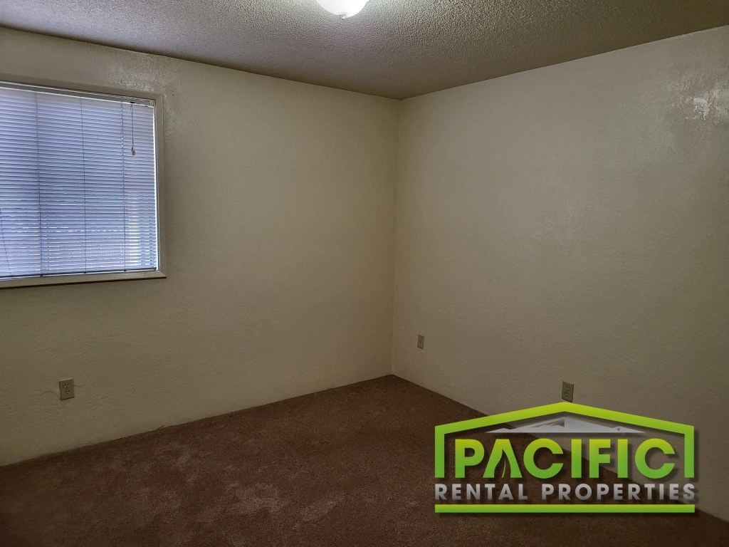 the interior of an empty room with a window and the pacific rental properties logo
