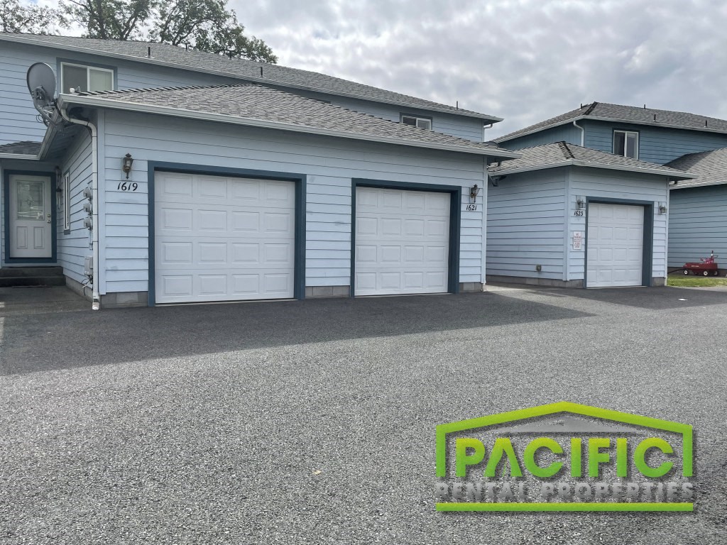a driveway in front of a house with white garage doors