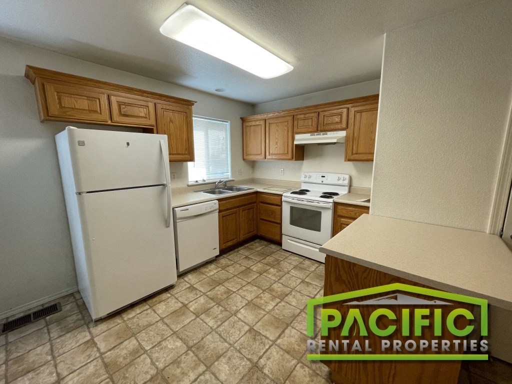 a kitchen with white appliances and wooden cabinets