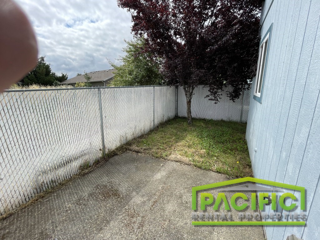 a backyard with a white fence and a tree