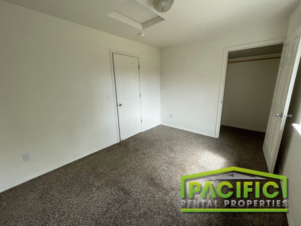 a room with a carpeted floor and a door to a closet