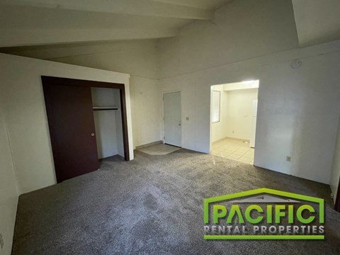 an empty living room in a residential home with carpet and a door to a closet