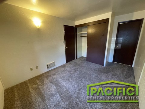 an empty living room with a carpeted floor and two doors