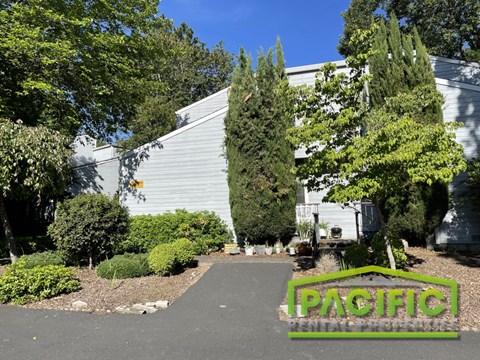 the front of a white building with a sign that says pacific on the driveway