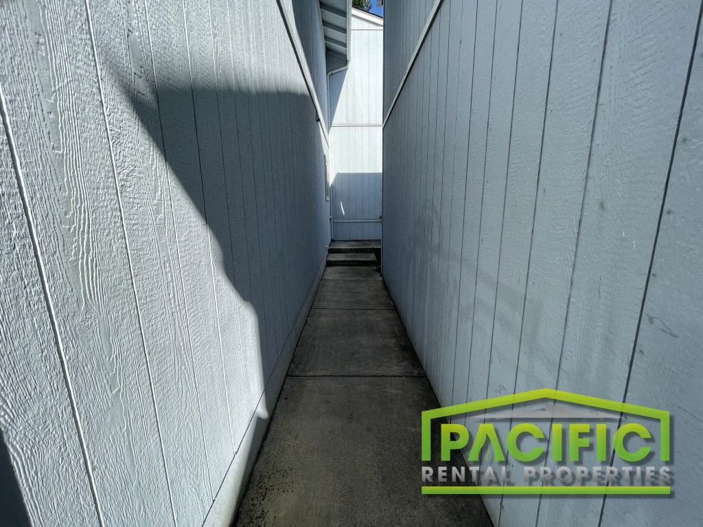 a narrow corridor with a shadow on the side of a building