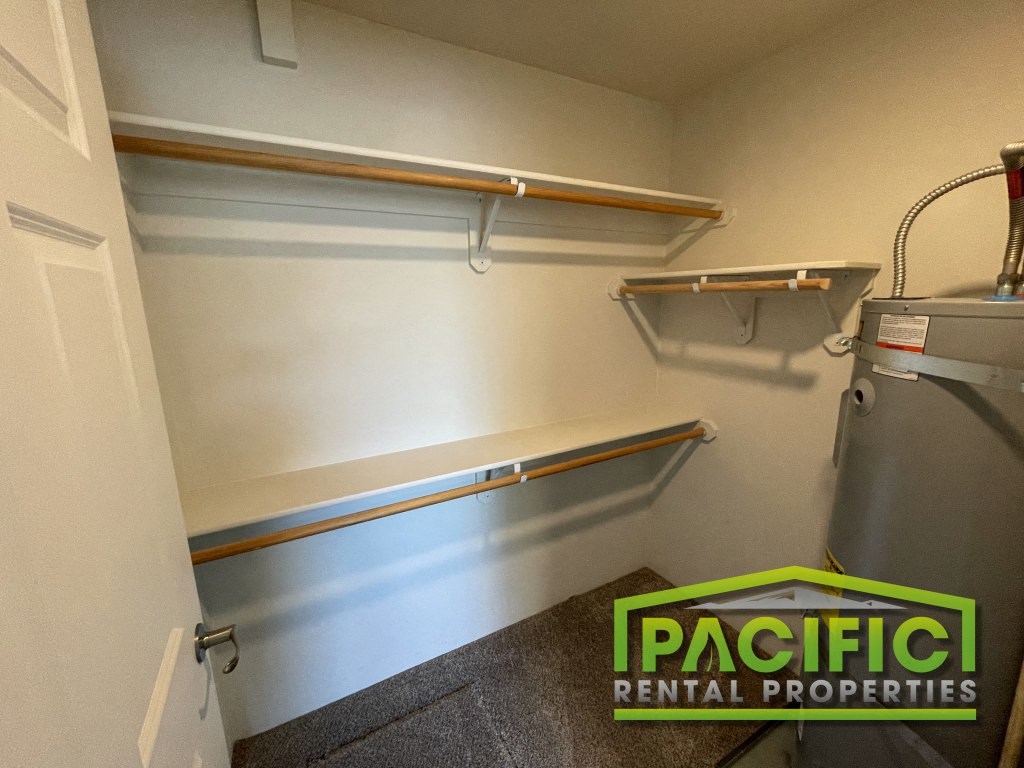 a small closet with a dryer and shelves on the wall