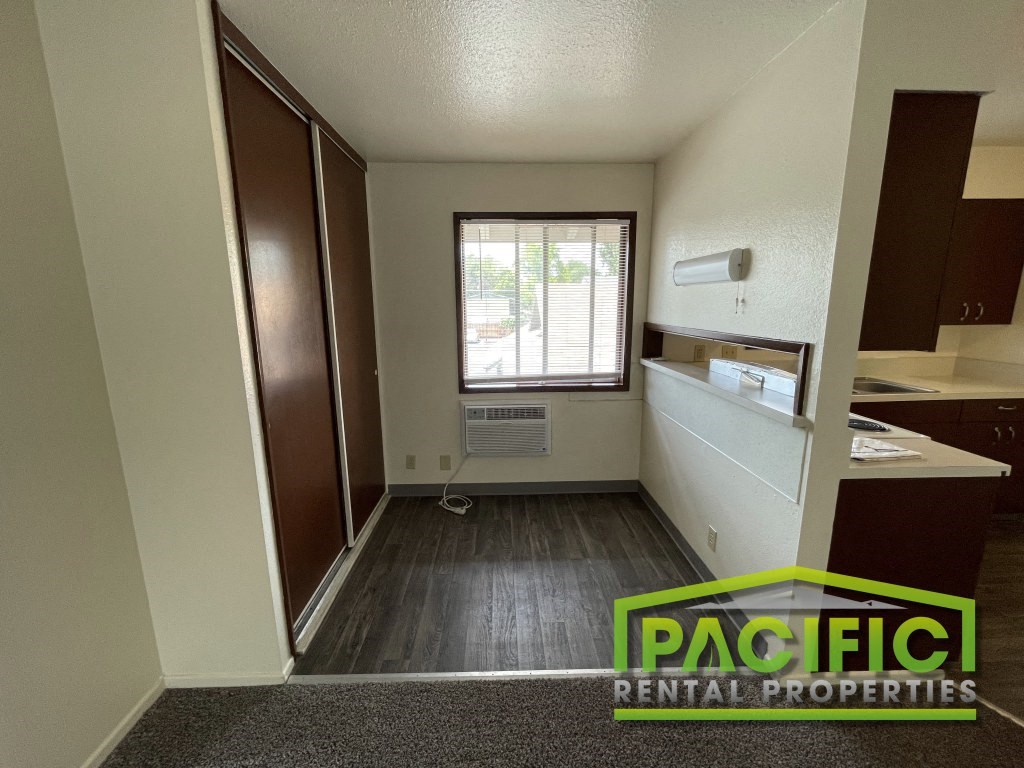 an empty room with a window and a kitchen