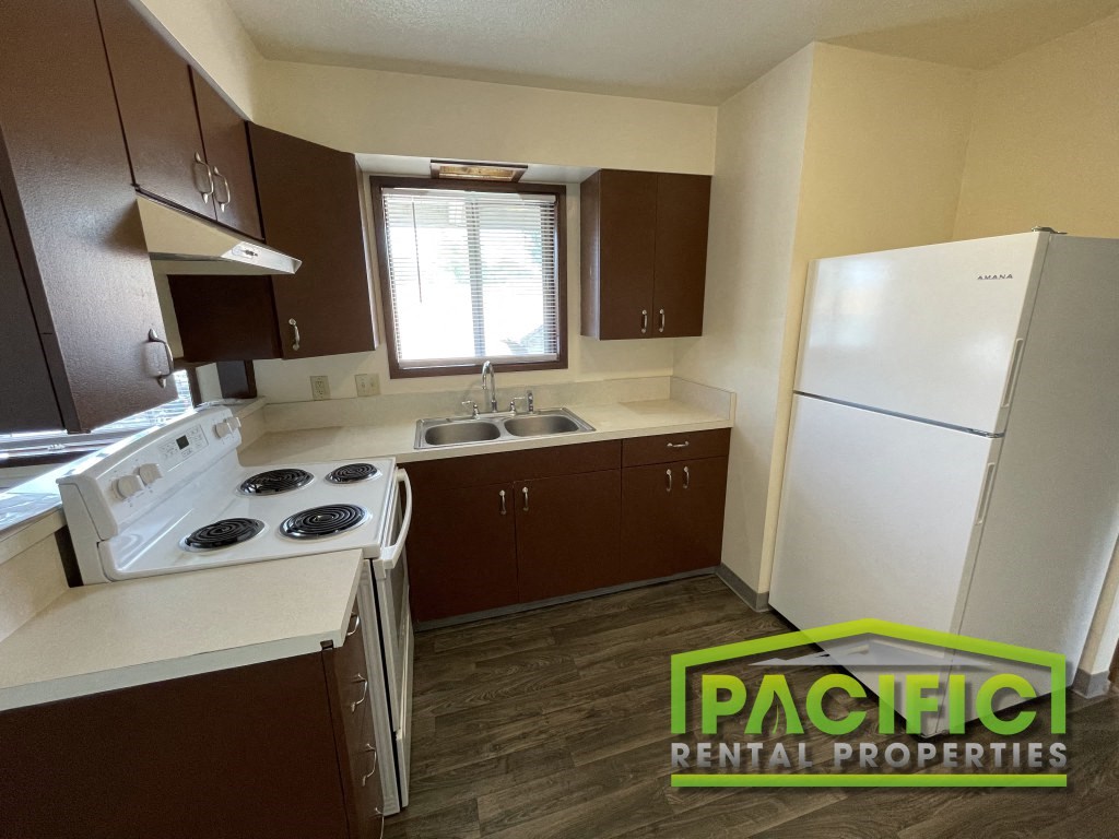 a small kitchen with white appliances and brown cabinets