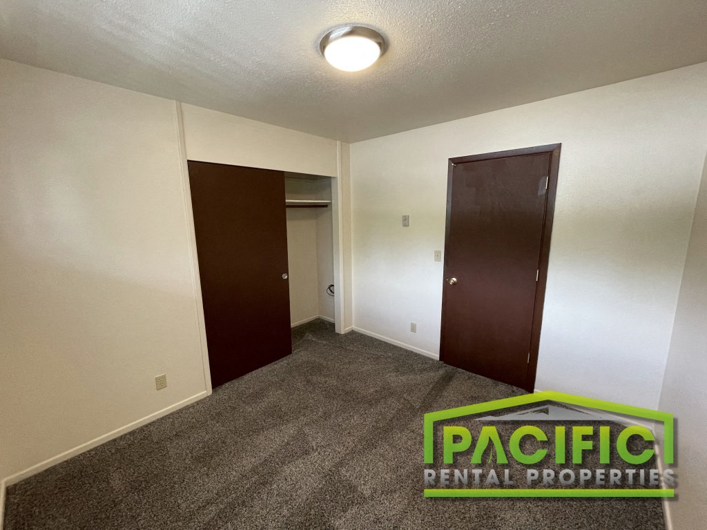 a room with a carpeted floor and a door to a closet