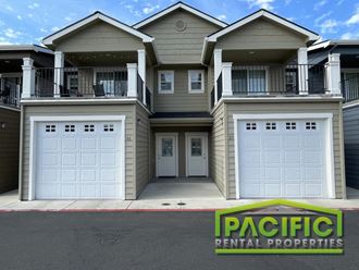 an apartment building with white garage doors and a pacific rental properties sign