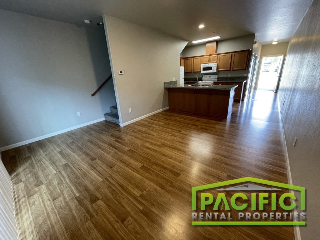 an empty living room and kitchen with wooden floors