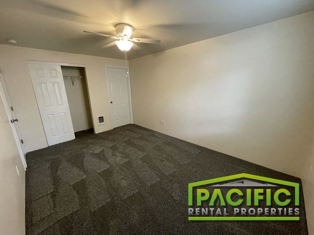 a living room with a carpeted floor and a ceiling fan