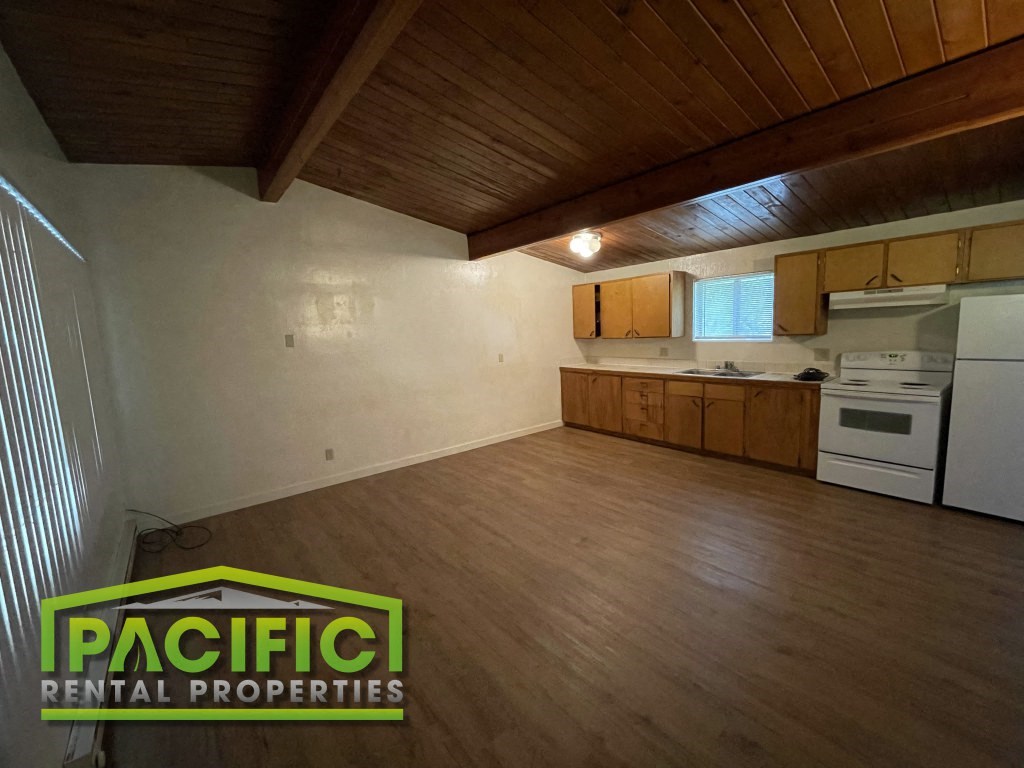 an empty kitchen with wooden floors and white appliances