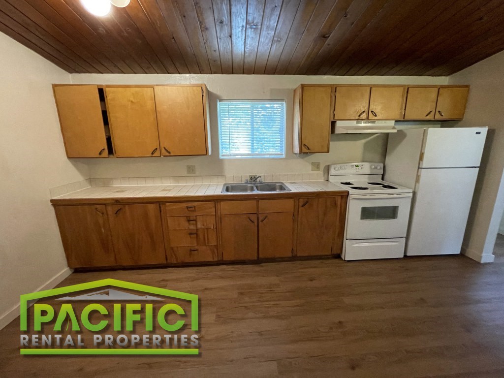 an empty kitchen with wooden cabinets and white appliances