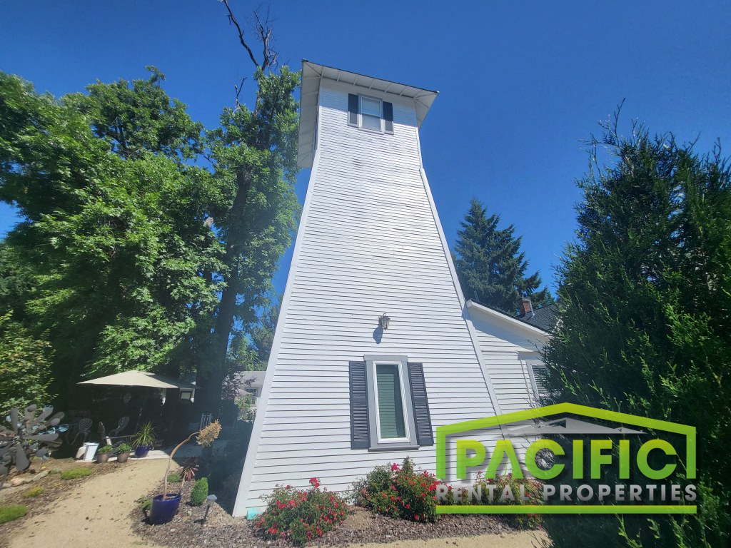 A white house with a green logo for Pacific Rental Properties in front of it.