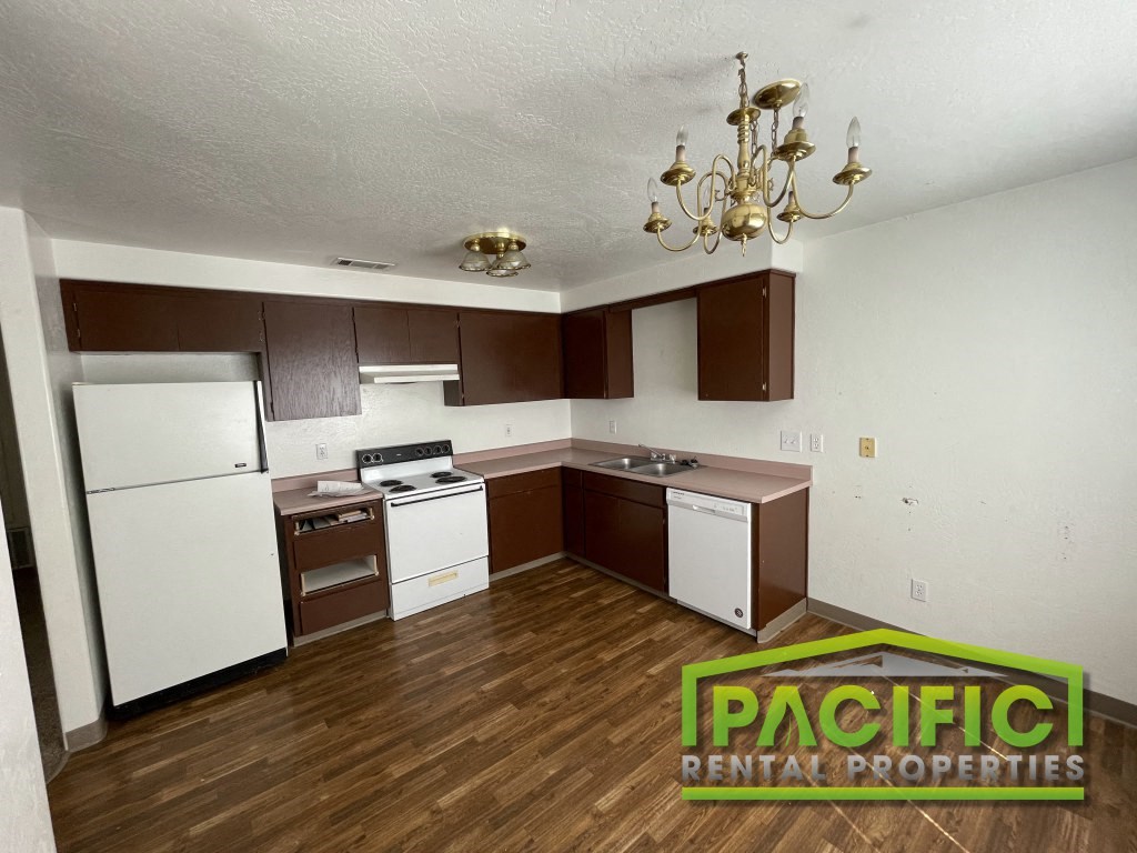 a renovated kitchen with white appliances and a chandelier
