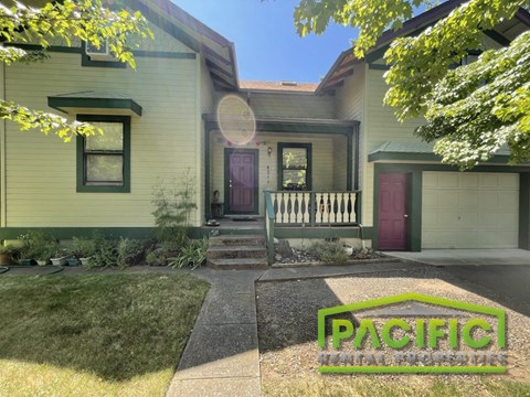 front view of a green house with a porch and a front lawn