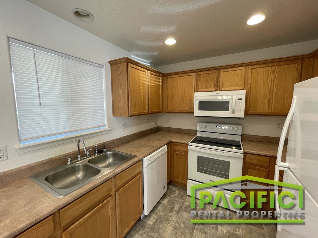 a kitchen with white appliances and wooden cabinets