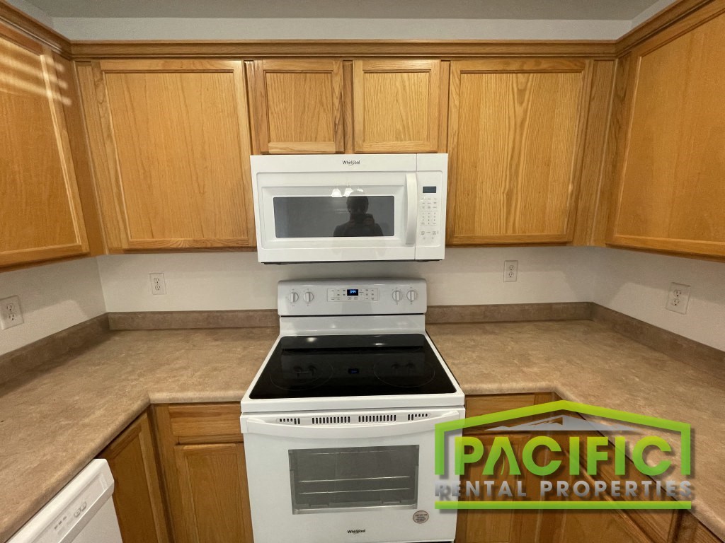a kitchen with white appliances and wooden cabinets
