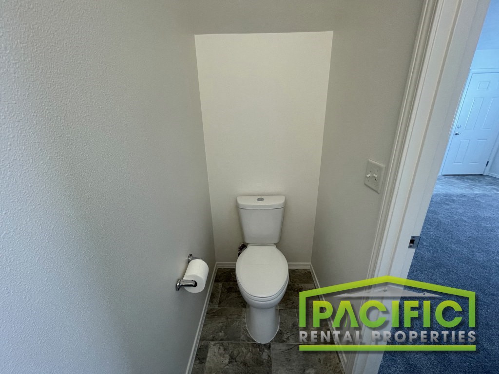 a small bathroom with a toilet and a roll of toilet paper