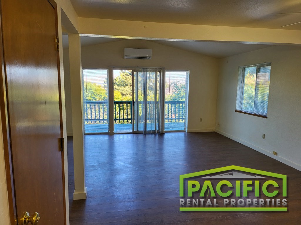 an empty living room with a balcony and pacific dental properties logo on the floor