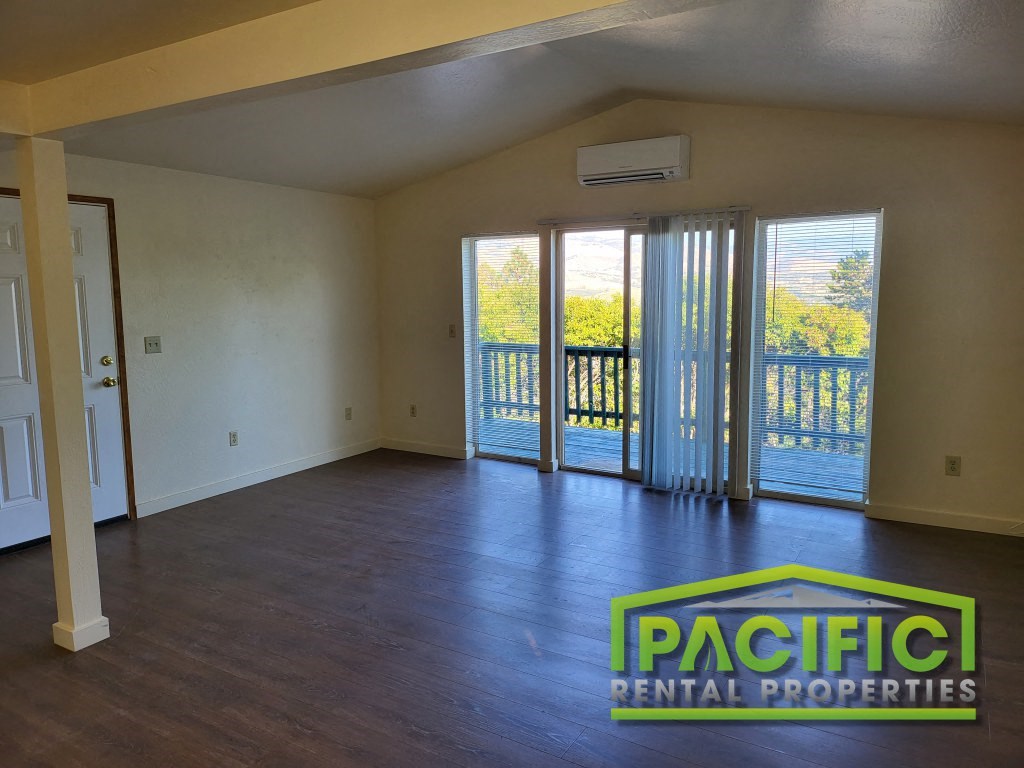 an empty living room with wood floors and a balcony